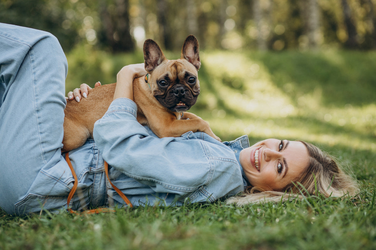 A woman spending time outdoors with her French bulldog